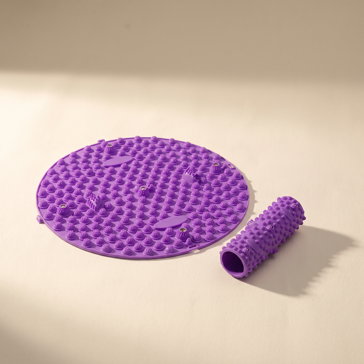 Foot massage pad and roller on a warm off-white surface