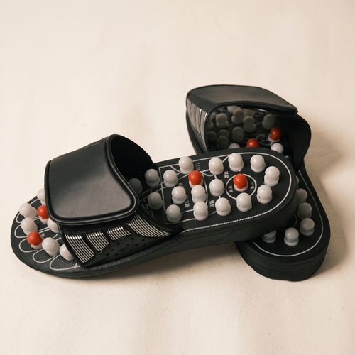 A pair of acupressure sandals on a warm off-white surface